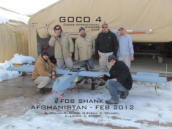 L to R: G. Rowley, S. Morse, M. Strine, C. DeLaney, H. Loving, and C. Brown. Members of the Cigars International Smokers Club posing with one of their drones in Afghanistan.