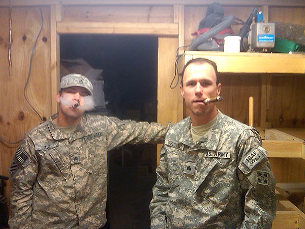 2 soldiers enjoying cigars while stationed in Afghanistan