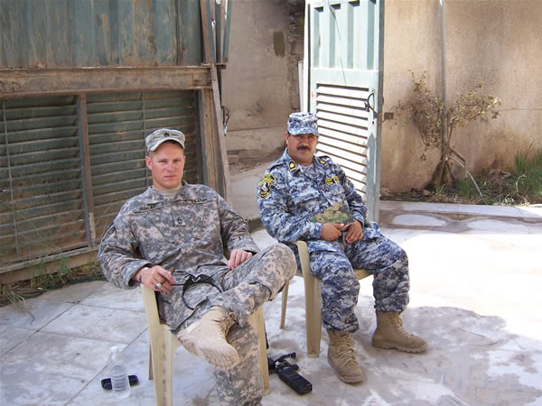 SFC Christopher Dunlap, sits out on the patio discussing some training with the Battalion Command Sergeant Major, CSM Sitar at the Iraqi National Police Battalion while enjoying a La Herencia Cubana cigar.